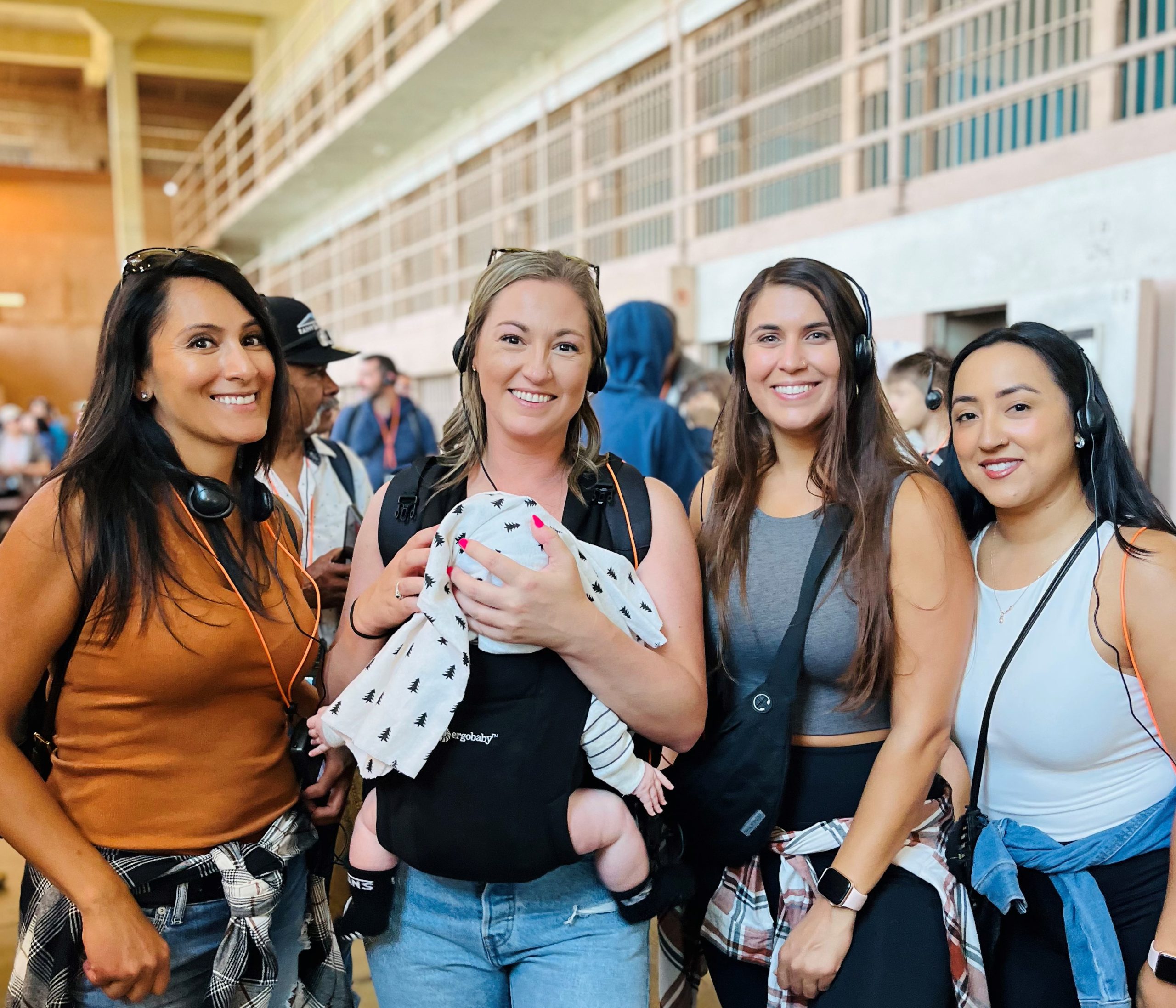 Four San Quentin Rehabilitation Center staff members, one holding a baby, on a tour of Alcatraz prison.