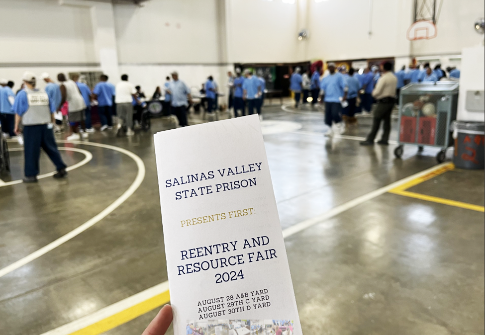Salinas Valley State Prison reentry and resource fair 2024 pamphlet with people seen in the background.
