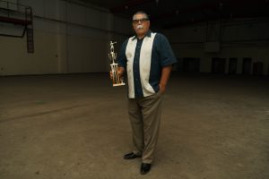 A formerly incarcerated youth, now four decades later, holding his boxing trophy.