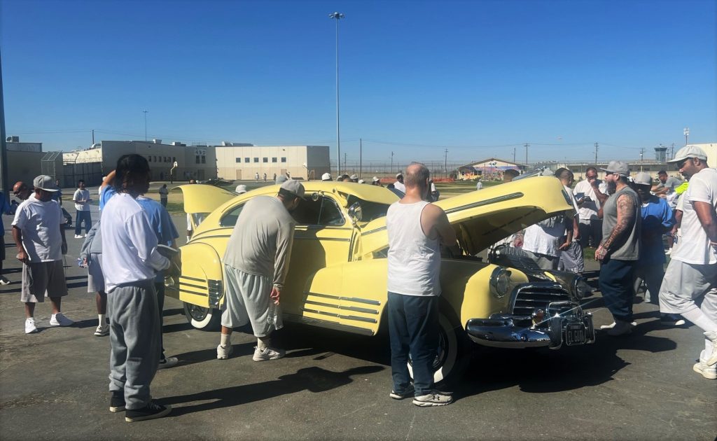 Classic 1946 Chevrolet vehicle with incarcerated people checking out the car on a prison yard at Avenal.