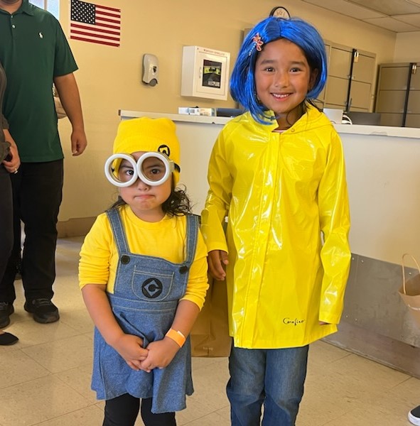 Two children, one dressed as a Minion and the other as Coraline Jones from the "Coraline" movie and illustrated book. 