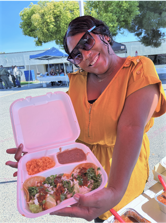 A woman holds a take-out tray of food at the Avenal State Prison CDCR health fair. 
