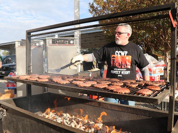 A retired officer works the barbecue grill at the family night event.