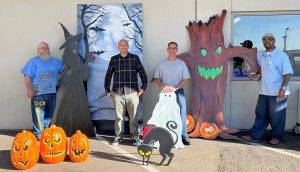 A staff member and incarcerated artists with painted and cutout Halloween decorations.