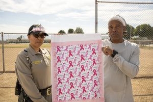 Incarcerated person and a staff member with a banner of names of people who've passed away from cancer.