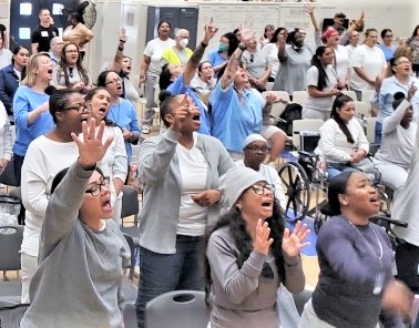 A group of incarcerated people with the hands raised in the air. 