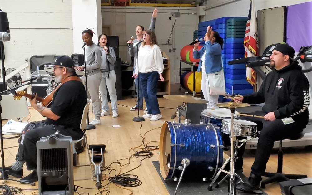 Incarcerated people and a band on a stage. 