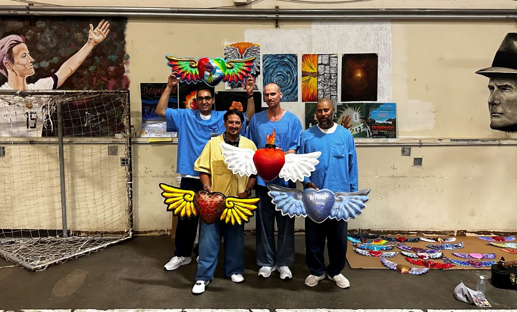 Soledad incarcerated artists hold some of their art work.