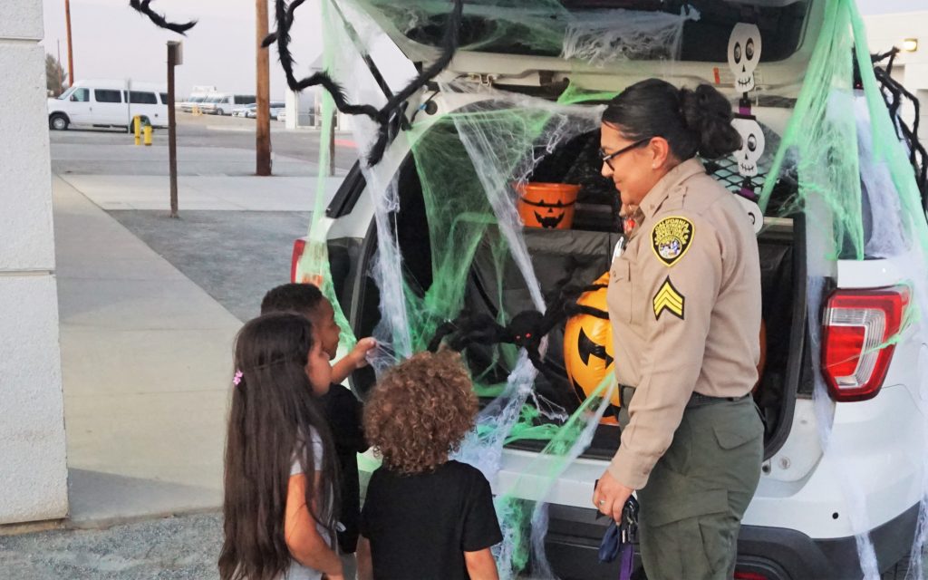 Prison visiting sergeant with children for trunk-or-treat.