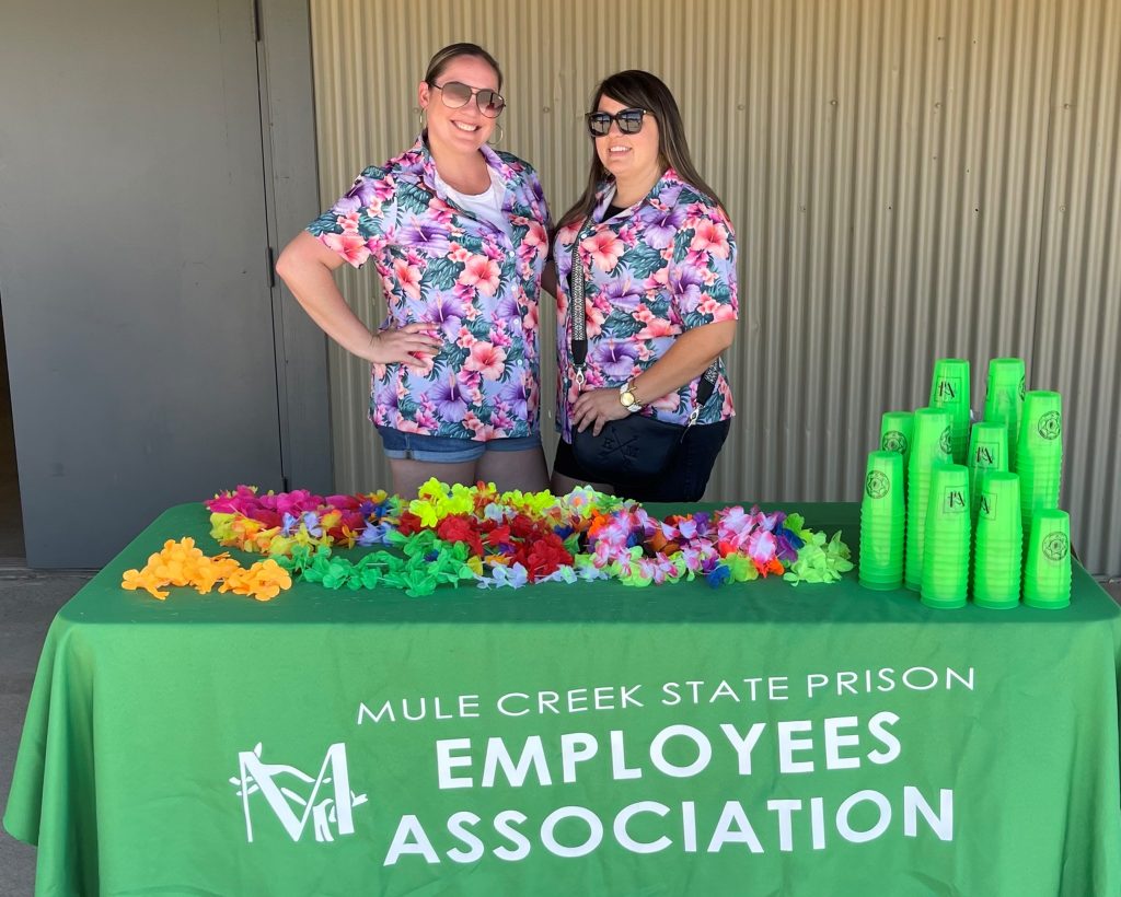 Two women standing at a table for the Mule Creek State Prison Employees Association.