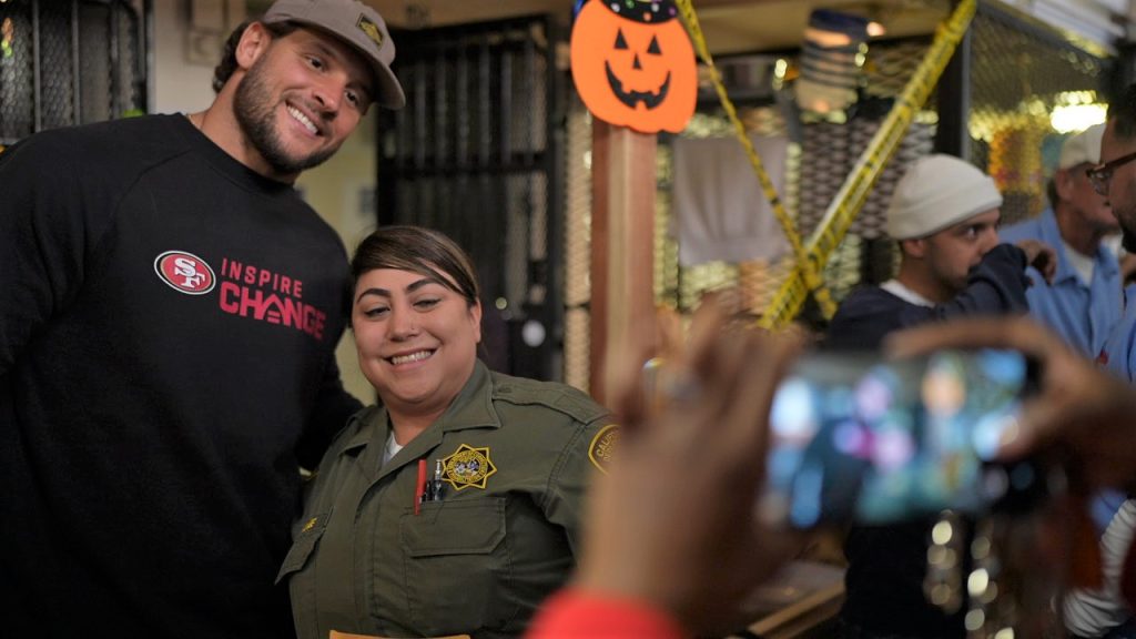 A team member poses for a photo with a San Quentin officer.