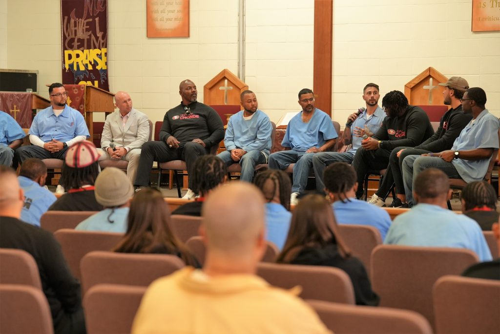 Group photo of 49ers representatives, San Quentin staff and incarcerated people in the chapel for a discussion about rehabilitation.