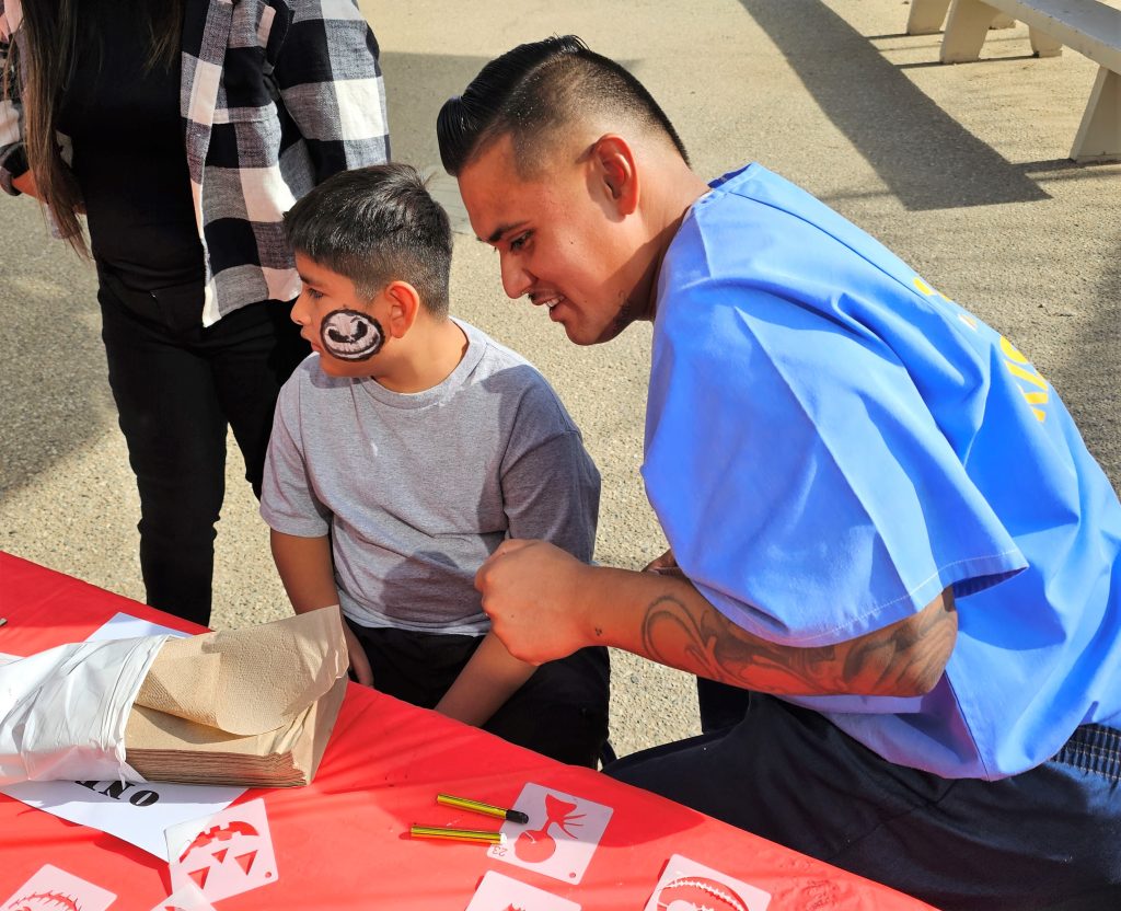 Using stencils, incarcerated people painted Halloween images on their children's faces.