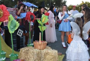 People wearing costumes at a Wizard of Oz themed trunk-or-treat area.