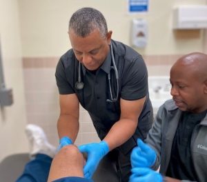 Nurse Practitioner Anthony Hales works on a patient's knee at SATF.