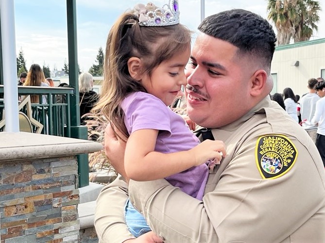 A new officer hugs a child after his graduation.
