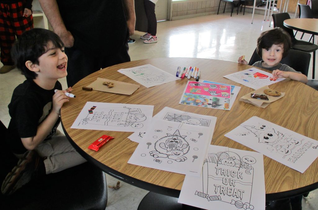 Children at a table color Halloween pages. 