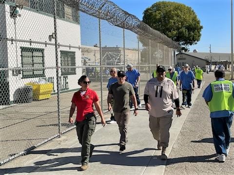 People walking beside a fence.