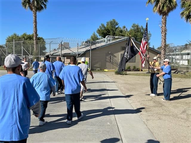 Walking for veterans at CIM beside two people holding flags.