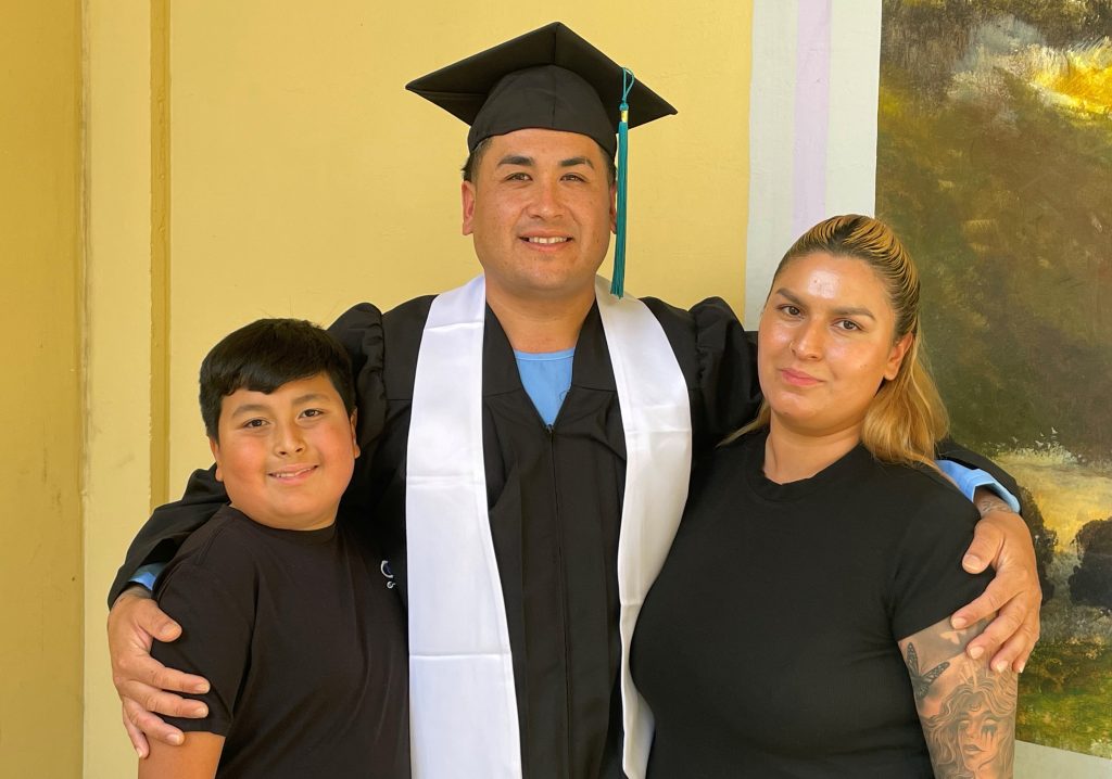 A woman and child stand beside a graduate at CMC.