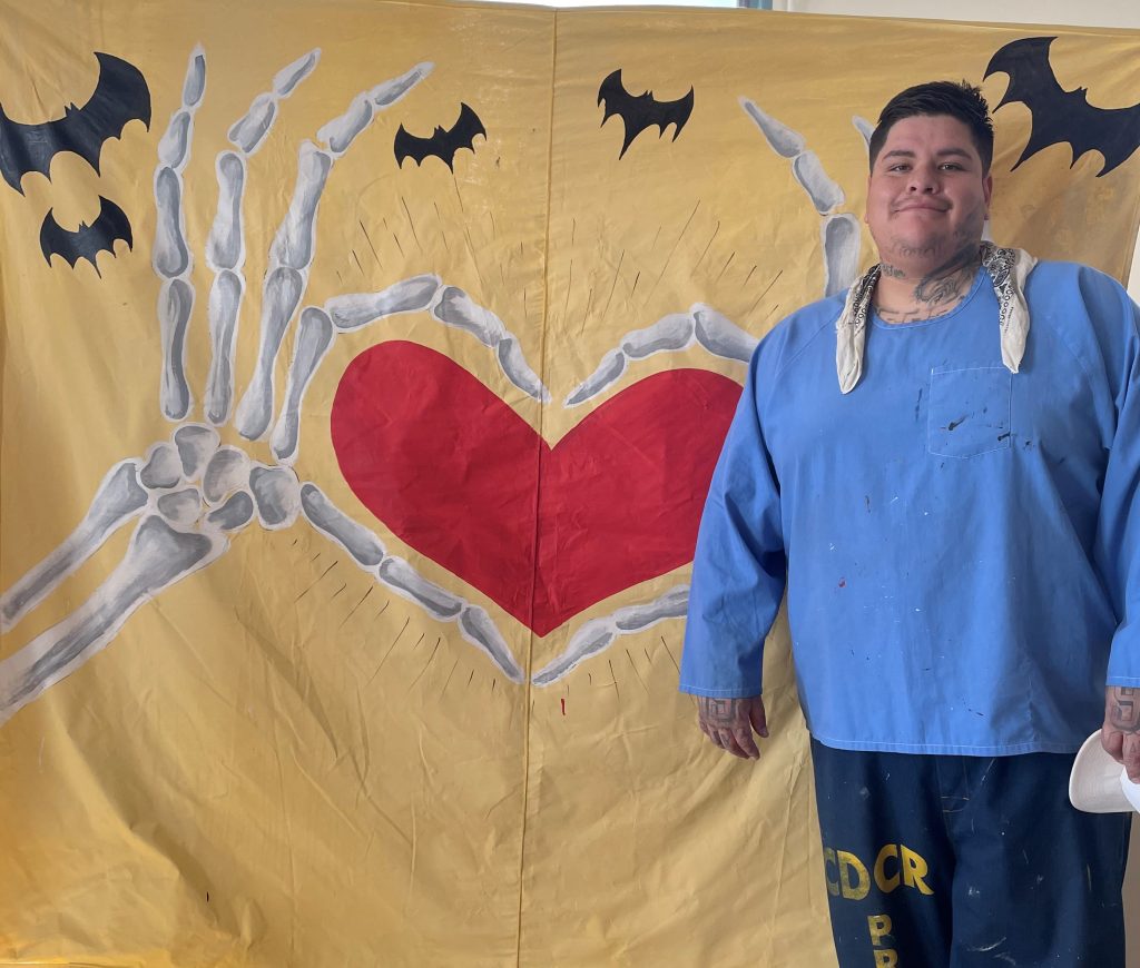 An incarcerated artist and a Halloween painting for visiting at California Correctional Institution, Tehachapi.