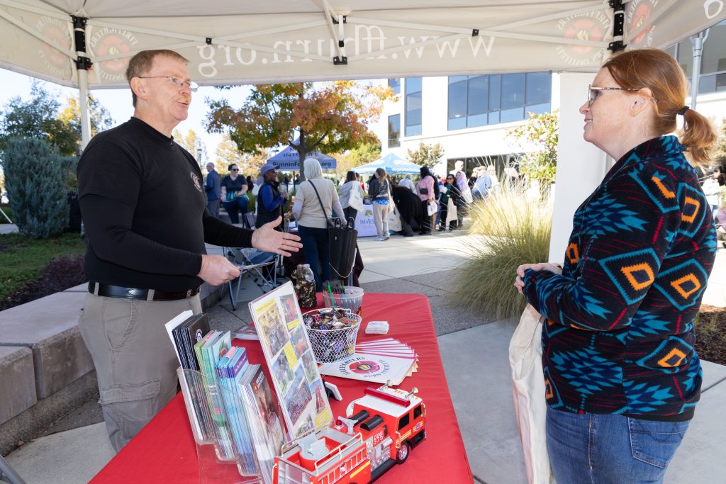 A volunteer speaking to another person at an information booth.