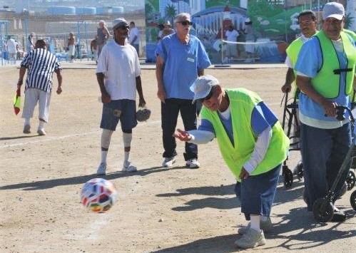 An incarcerated person rolls the ball back onto the field.