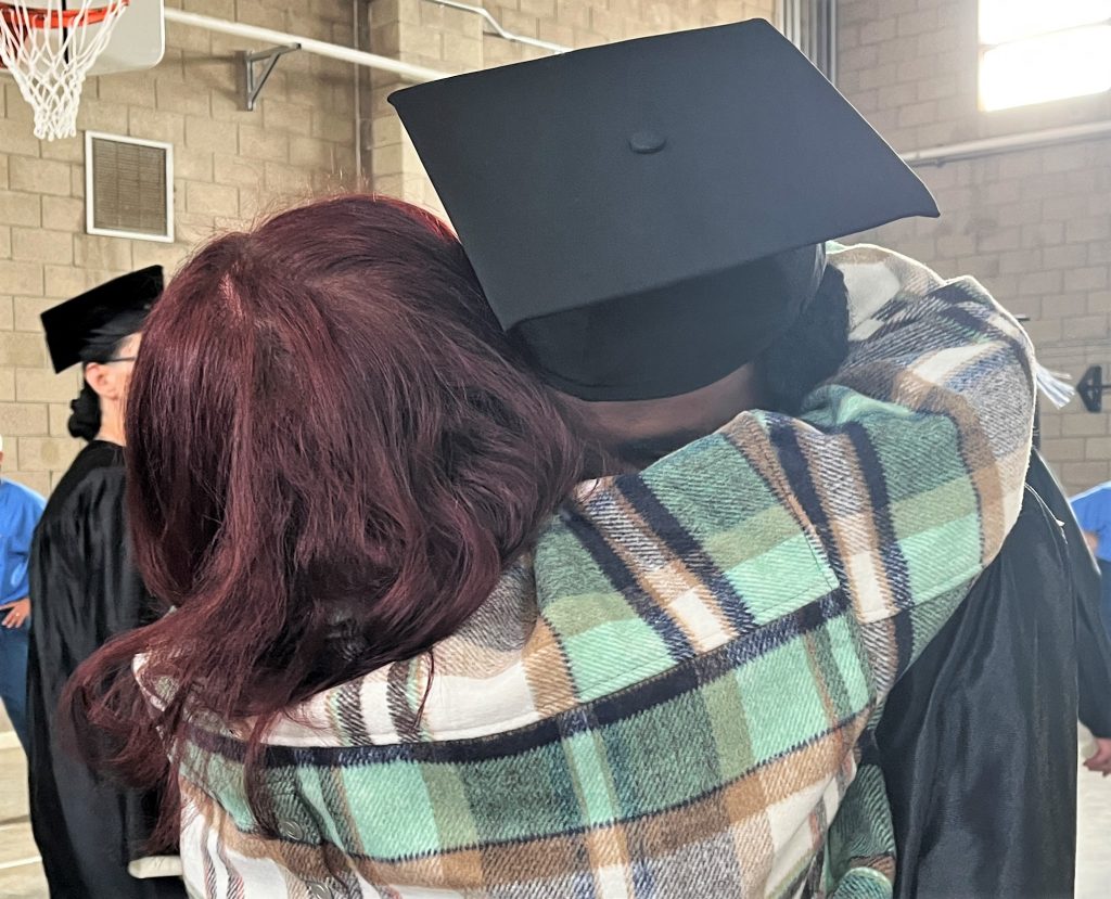Gradate receives a hug from a family member after the ceremony at Valley State Prison.