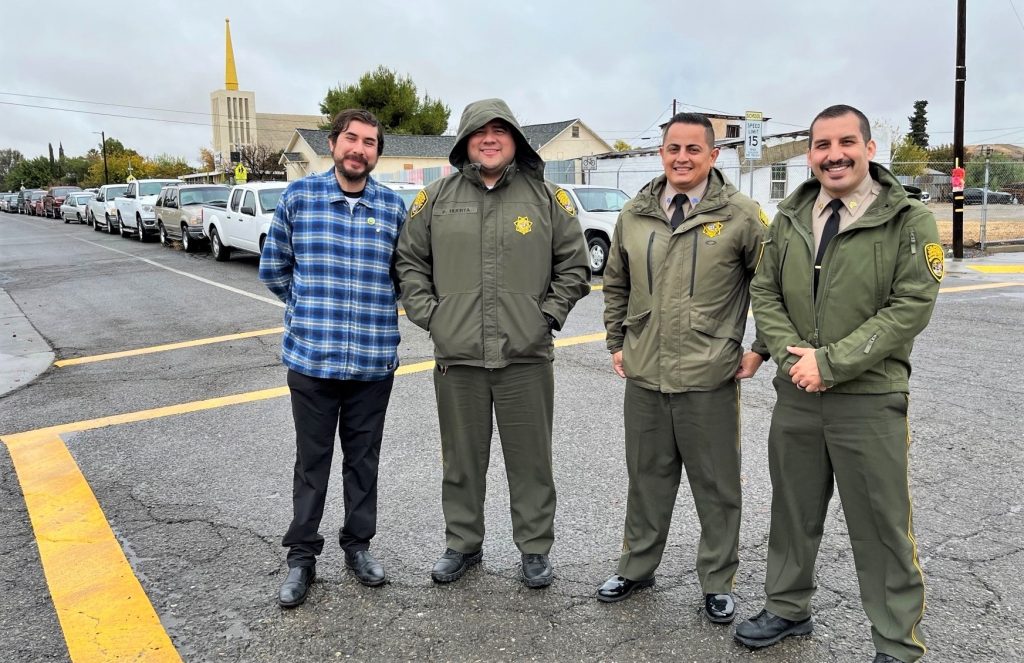 Avenal State Prison staff prepare to distribute turkeys to the waiting line of cars behind them.