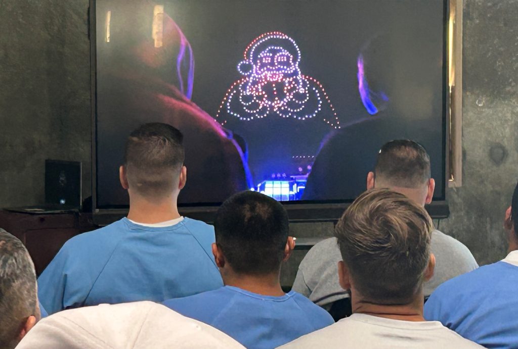 A holiday drone special was shown to the population at Avenal State Prison. In the background can be seen a drone light display of Santa Claus.