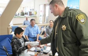 A visiting staff member presents a gift to a child at Avenal State Prison.