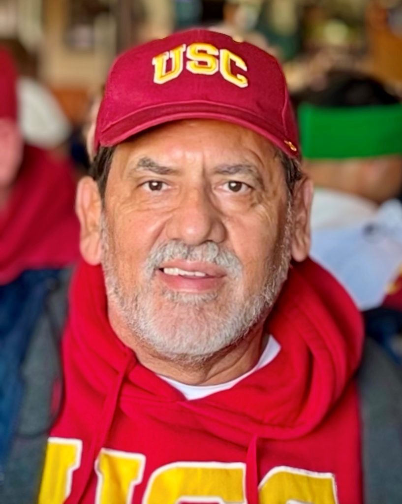 Louis Baltazar, retired captain, obituary image of him wearing USC hat and scarf.