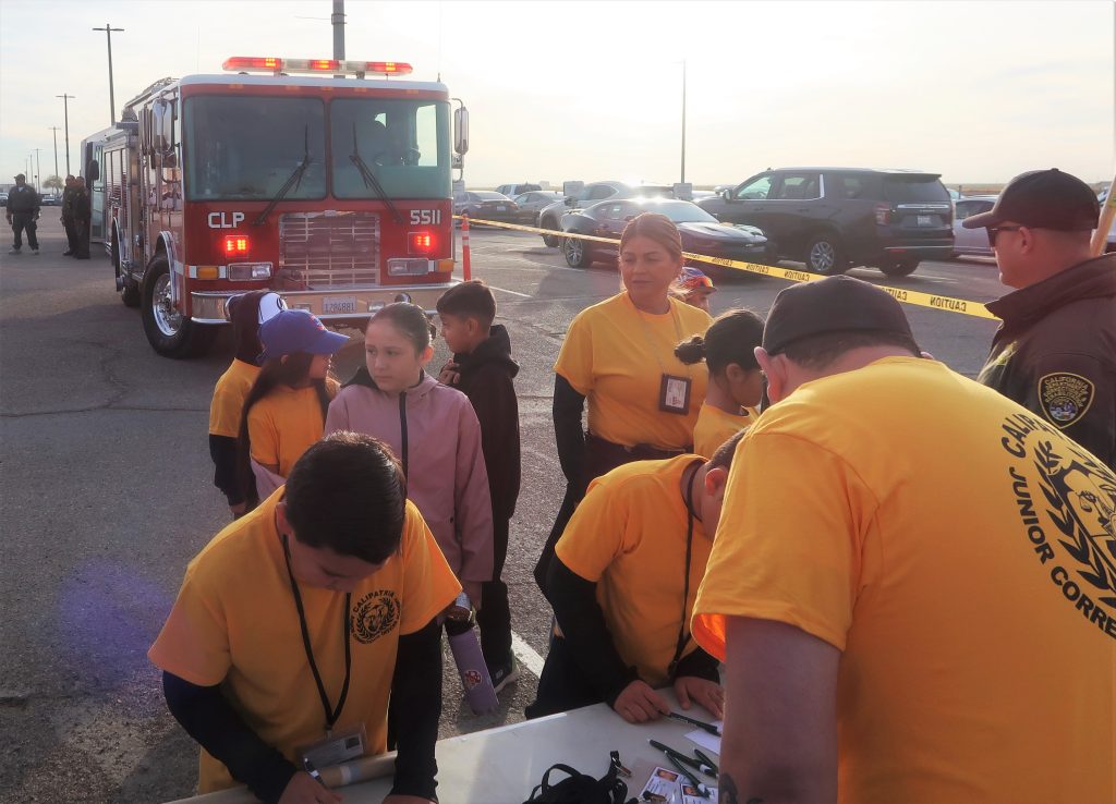 Kids and their parents register for the Calipatria junior academy while a fire engine can be seen behind them.