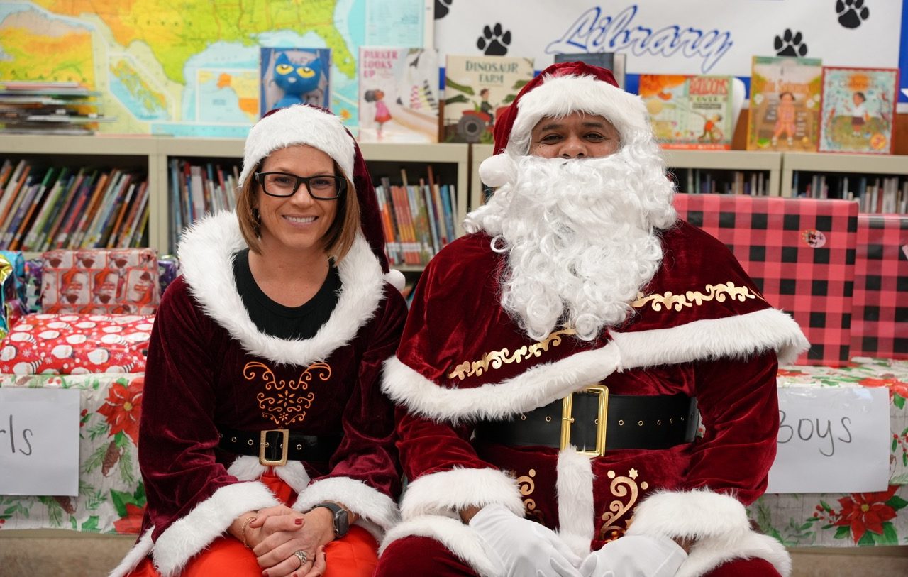 California Health Care Facility Warden Gena Jones as Mrs. Claus and retired Lt. Barry Tisdale as Santa sitting at an elementary school.