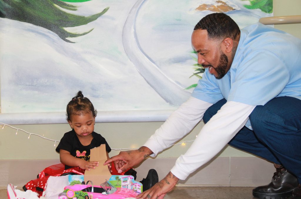 A child opens a present while visiting her incarcerated family member at CHCF in Stockton.