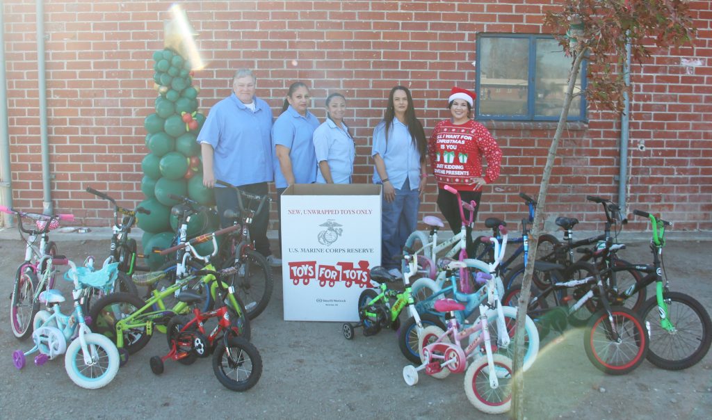 Refurbished bicycles from California Institution for Women with four incarcerated people and one staff member along with a Toys for Tots box. 