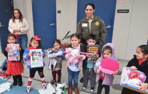 A correctional officer with kids opening gifts.