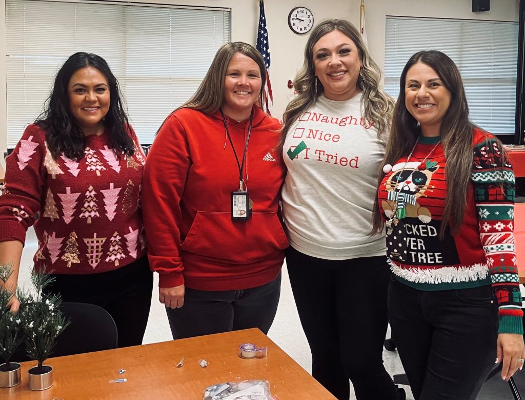 Four people wearing Christmas attire attend Pleasant Valley State Prison health care staff holiday lunch.