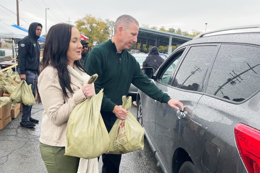 A man and woman carry bags of food to give to people for Thanksgiving, helping feed the hungry.
