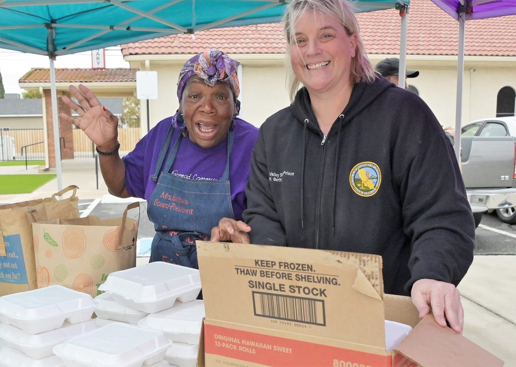 Two people at a table to help distribute food for Thanksgiving.
