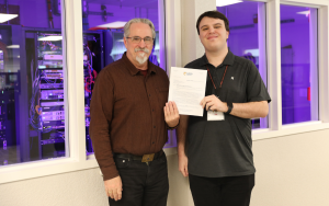 Two CALPIA staff members with a letter granting a cybersecurity grant from California Office of Emergency Services.