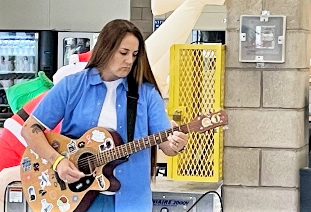 A woman playing guitar at a correctional facility graduation.