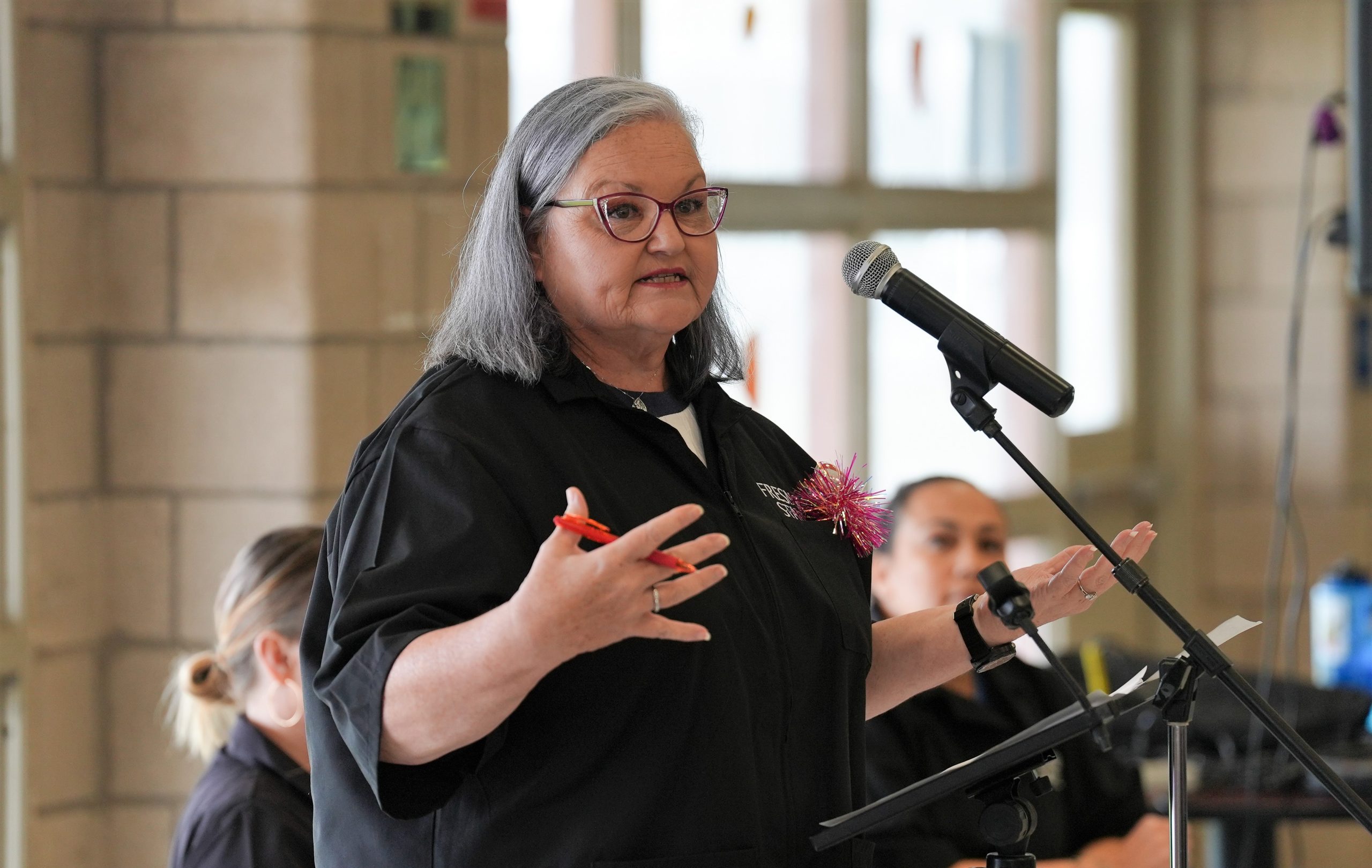 A woman speaks into a microphone at CCWF during a debate with other Fresno State University students.