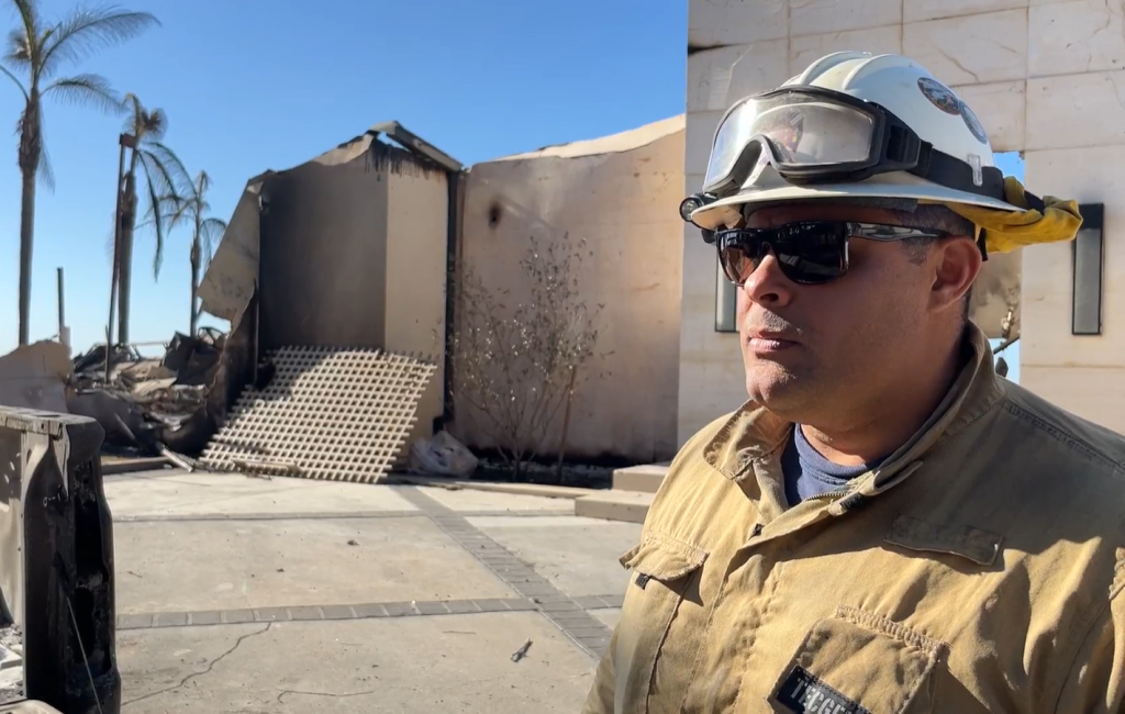 Fire chief with rubble and burned-out home behind him at the Southern California wildfires.