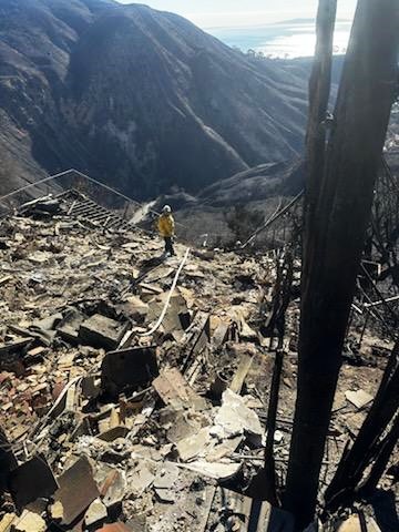 A team member surveys extensive damage in the Los Angeles Palisades area.