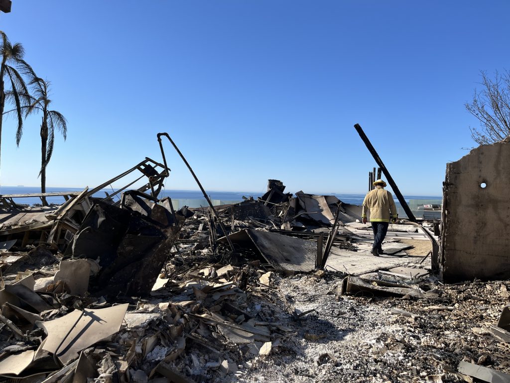 A strike team member walks through the rubble of a home in the Palisades.