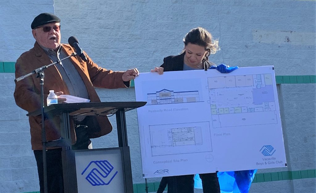 Two people hold plans for the new youth club. The CMF warden attended the press event. 