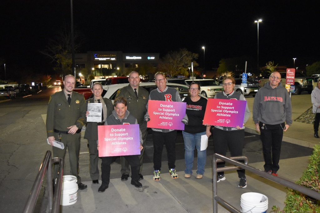 Law enforcement and volunteers holding donate to support Special Olympics signs