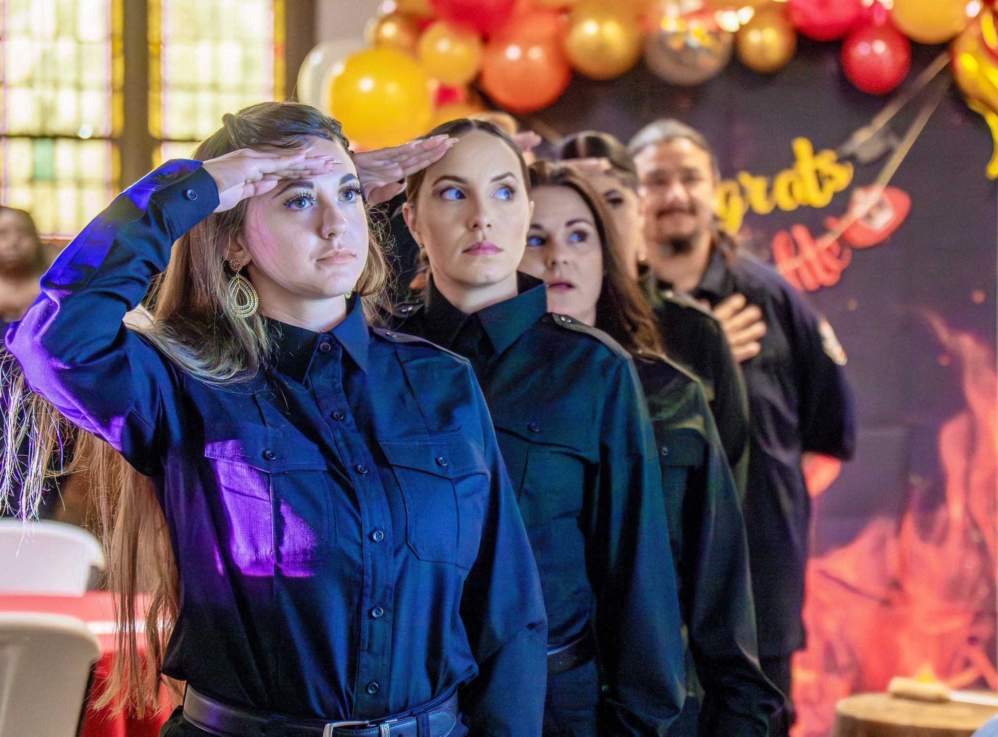 First all-female cohort graduates, standing in line at attention, at Future Fire Academy salute during ceremony.