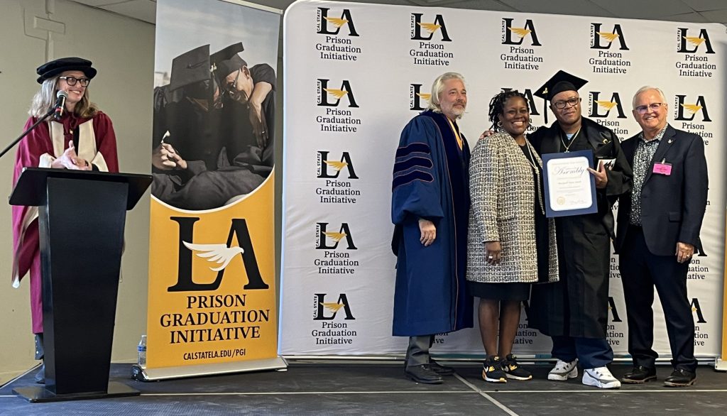A graduate poses for photos at California State Prison, Los Angeles County.